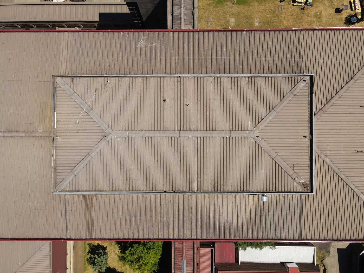 Top-down aerial view of a corrugated metal commercial roof with a large rectangular inset roof section