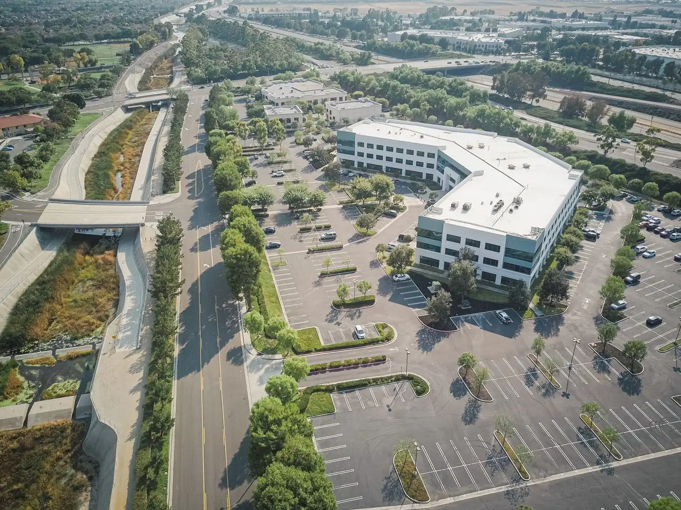 Aerial view of an office building with a bright white flat roof and large parking lots